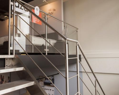 escalier en inox avec 2 limons, marches poinçonnées, rampe avec poteaux horizontales, balustrade en verre